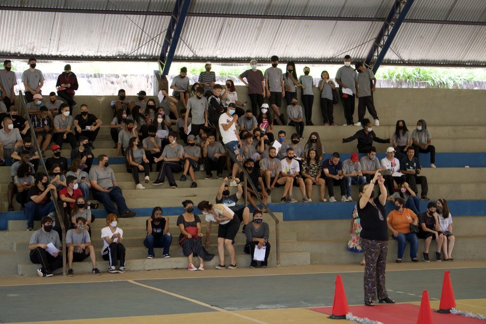 A arquibancada cheia de estudantes de máscara.