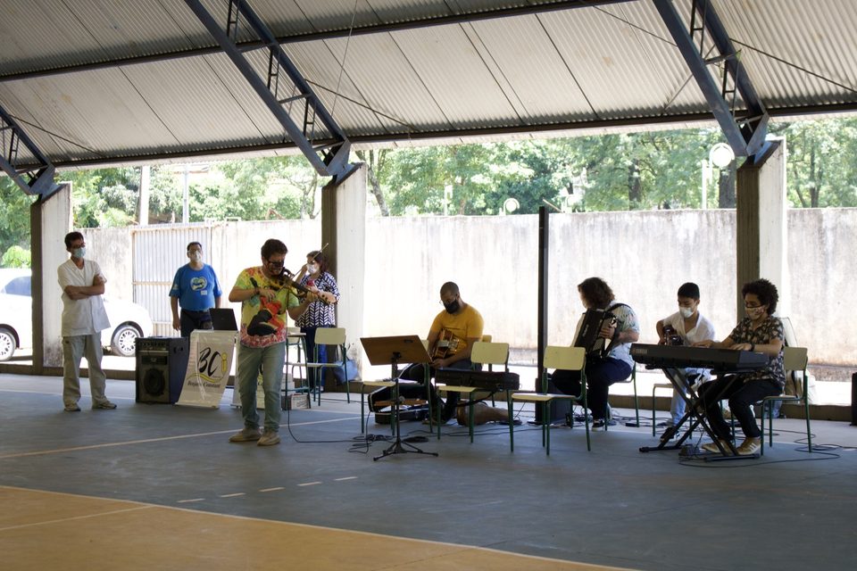 O grupo toca na quadra: violino, violão, sanfona e teclado.