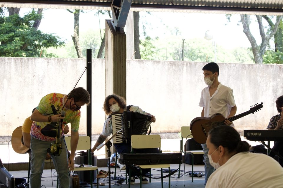 Roney Marczak, curvado, toca violino perto da sanfona e do violão.