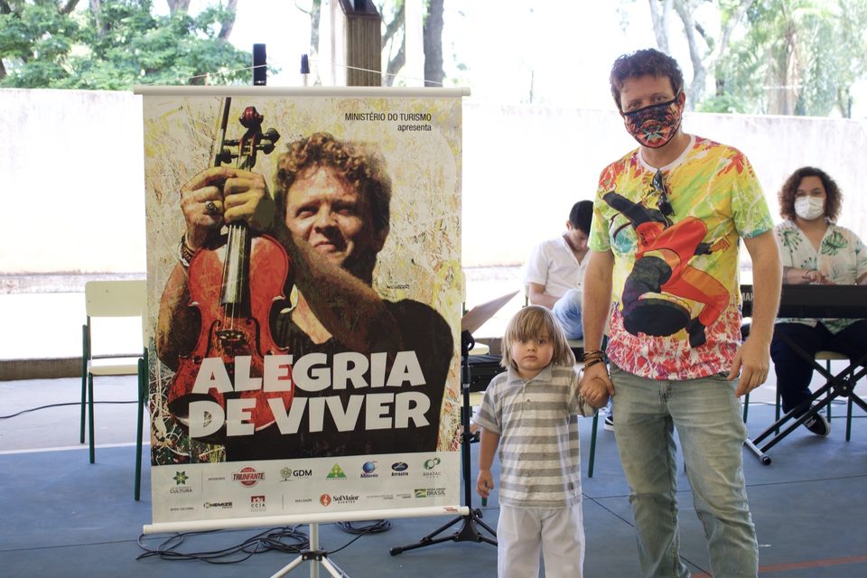 Roney Marczak e uma criança ao lado do banner do disco.