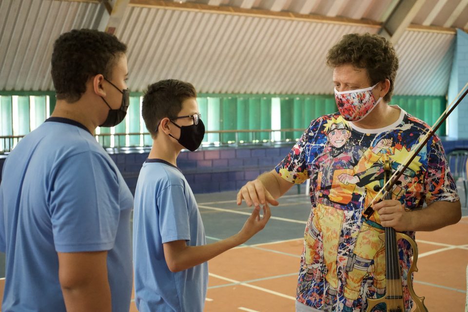 Roney Marczak cumprimenta dois estudantes de uniforme azul na quadra.