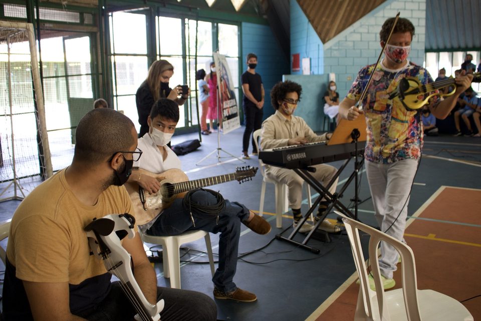 Músicos tocam teclado e violão na quadra; Roney Marczak toca violino de pé.