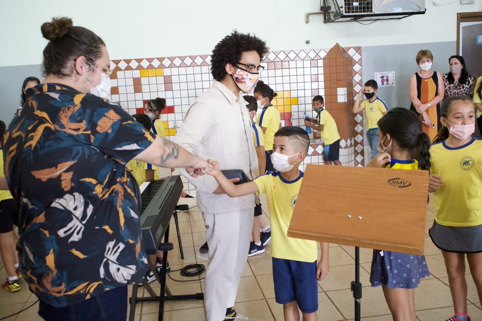 Crianças de uniforme amarelo cumprimentam os músicos antes da apresentação.