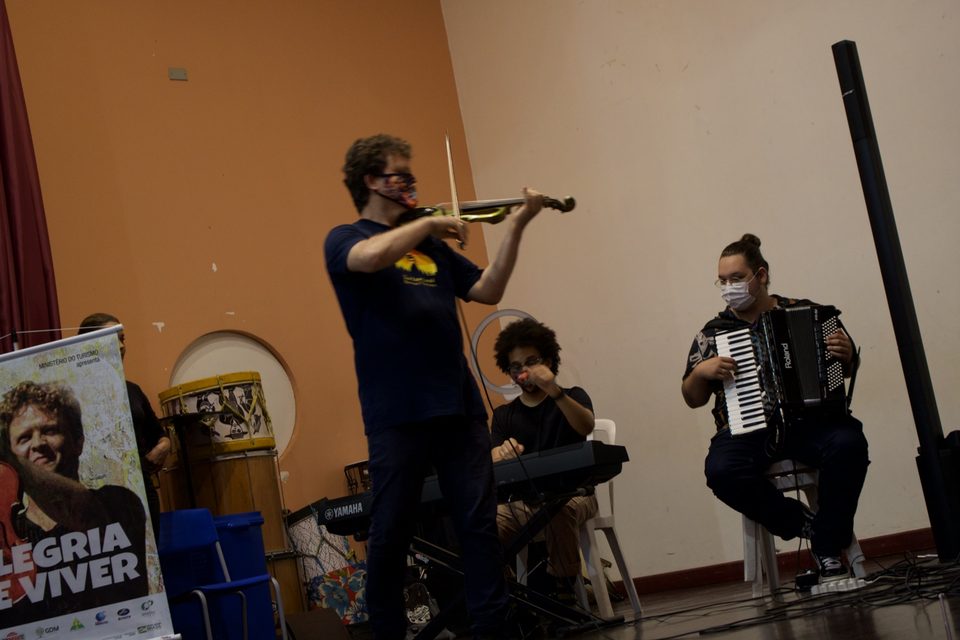 Roney Marczak toca violino de pé, ao lado da sanfona e do teclado.