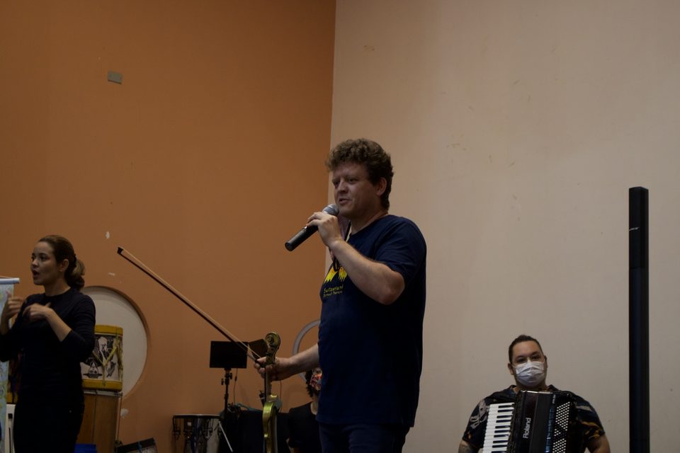 Roney Marczak fala ao microfone; ao lado, uma mulher gesticula.