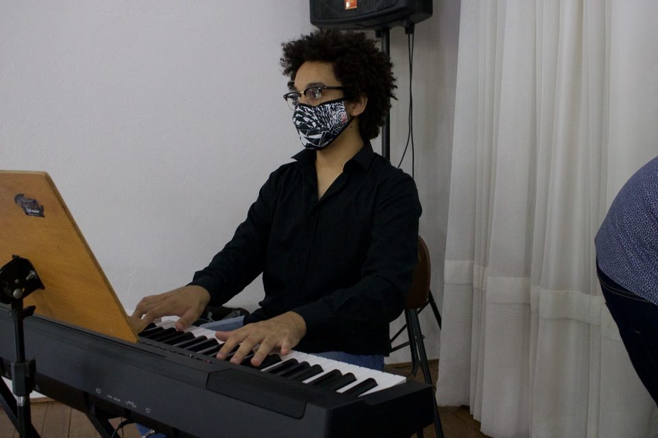 Um tecladista de máscara toca no palco.