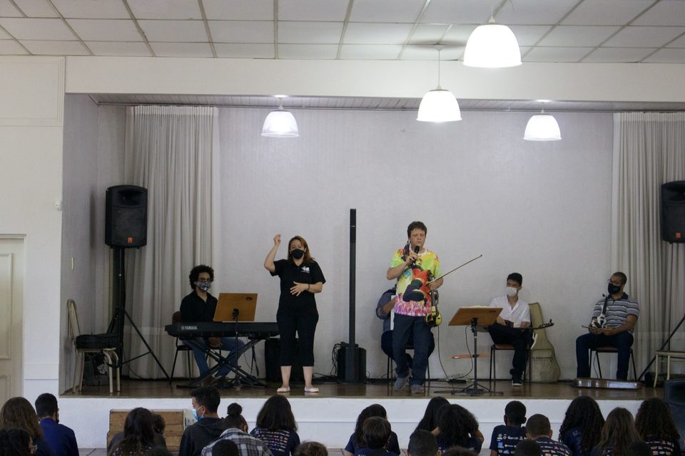 Uma mulher gesticula ao lado de Roney Marczak no palco.