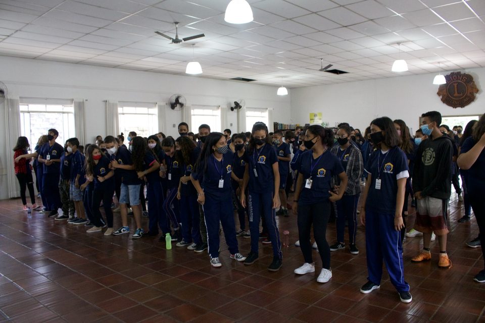Estudantes de pé no salão, ao fim da apresentação.