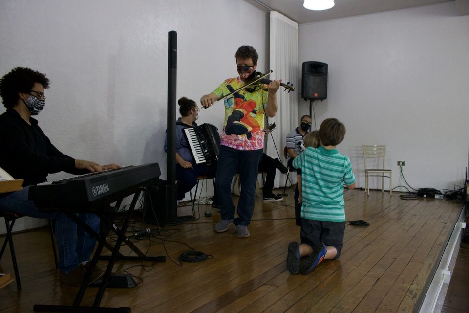 Um menino ajoelhado no palco ouve Roney Marczak tocar.