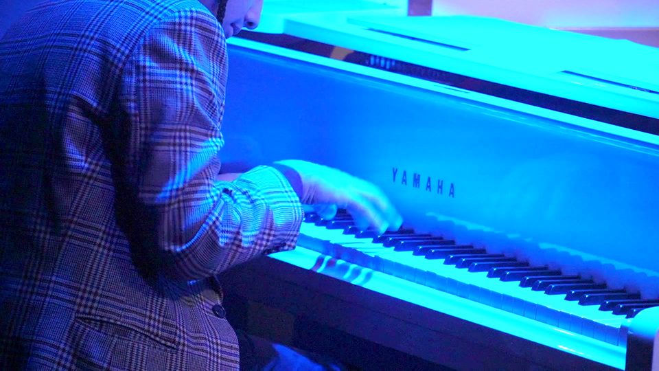 Mãos sobre o teclado do piano branco, em luz azul.